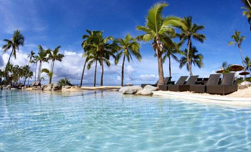 Piscina de arena de estilo tropical con palmeras